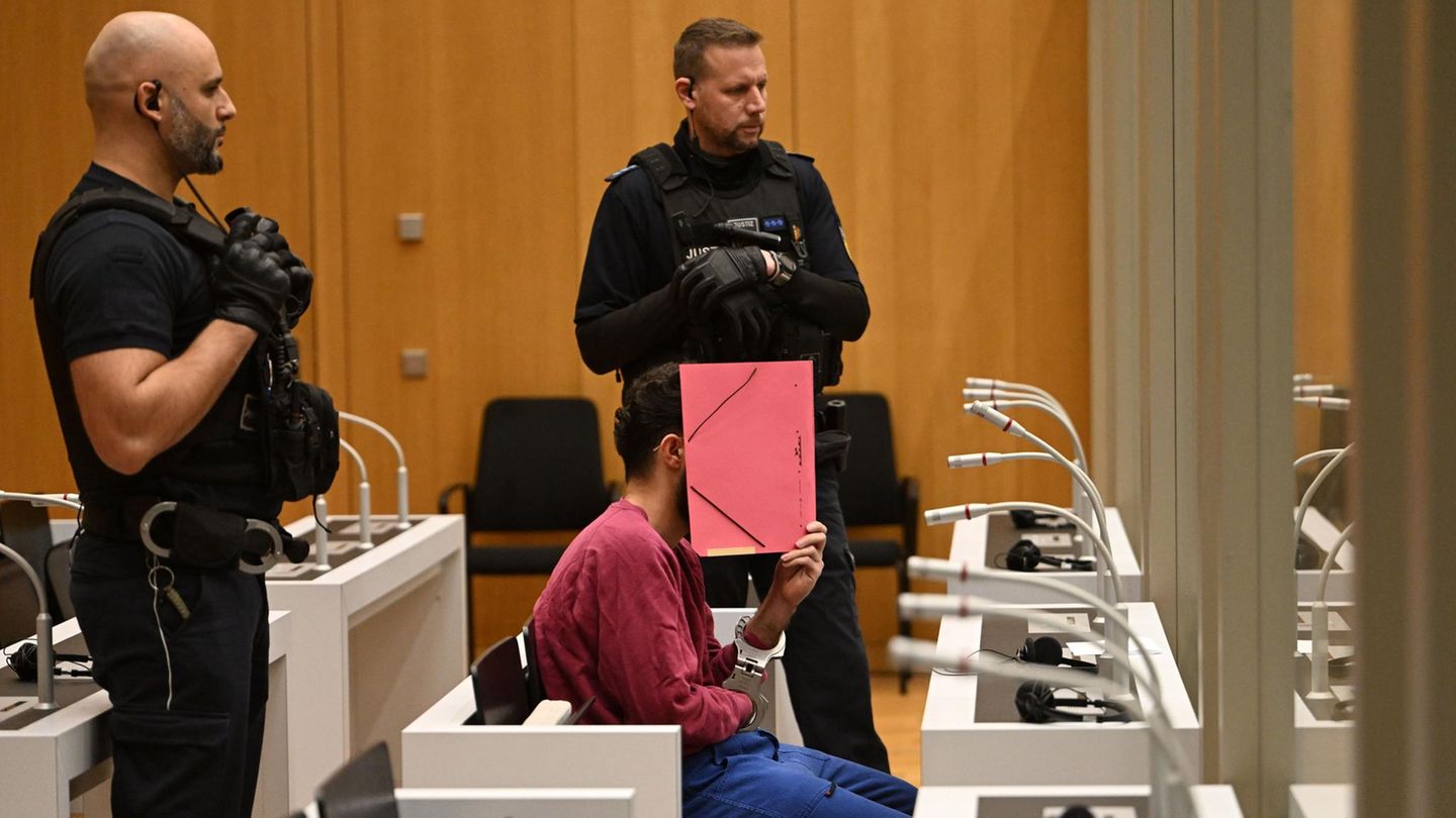 Mannheimer Messerattentäter Sulaiman Ataee Der mutmaßliche Messerattentäter von Mannheim sitzt im Gerichtssaal und verdeckt sein Gesicht mit einem Ordner.