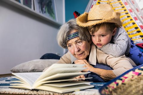 Späte Mutterschaft: Ältere Frau mit Kind auf dem Bauch liegend und lesend