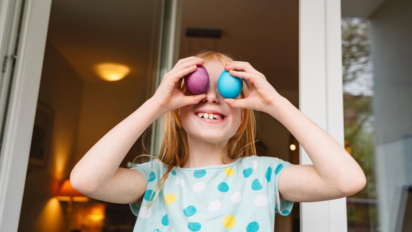 Ostereier kochen: Ein Kind hält sich bunte Ostereier vor die Augen.