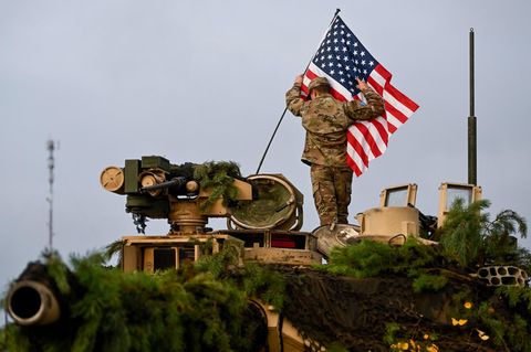Ein Soldat bringt bei einer Militärübung in Litauen eine US-Fahne an einem Militärfahrzeug an
