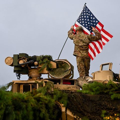 Ein Soldat bringt bei einer Militärübung in Litauen eine US-Fahne an einem Militärfahrzeug an