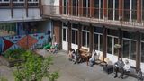 Im Innenhof der Schule sitzen fünf Menschen in der Sonne und rauchen