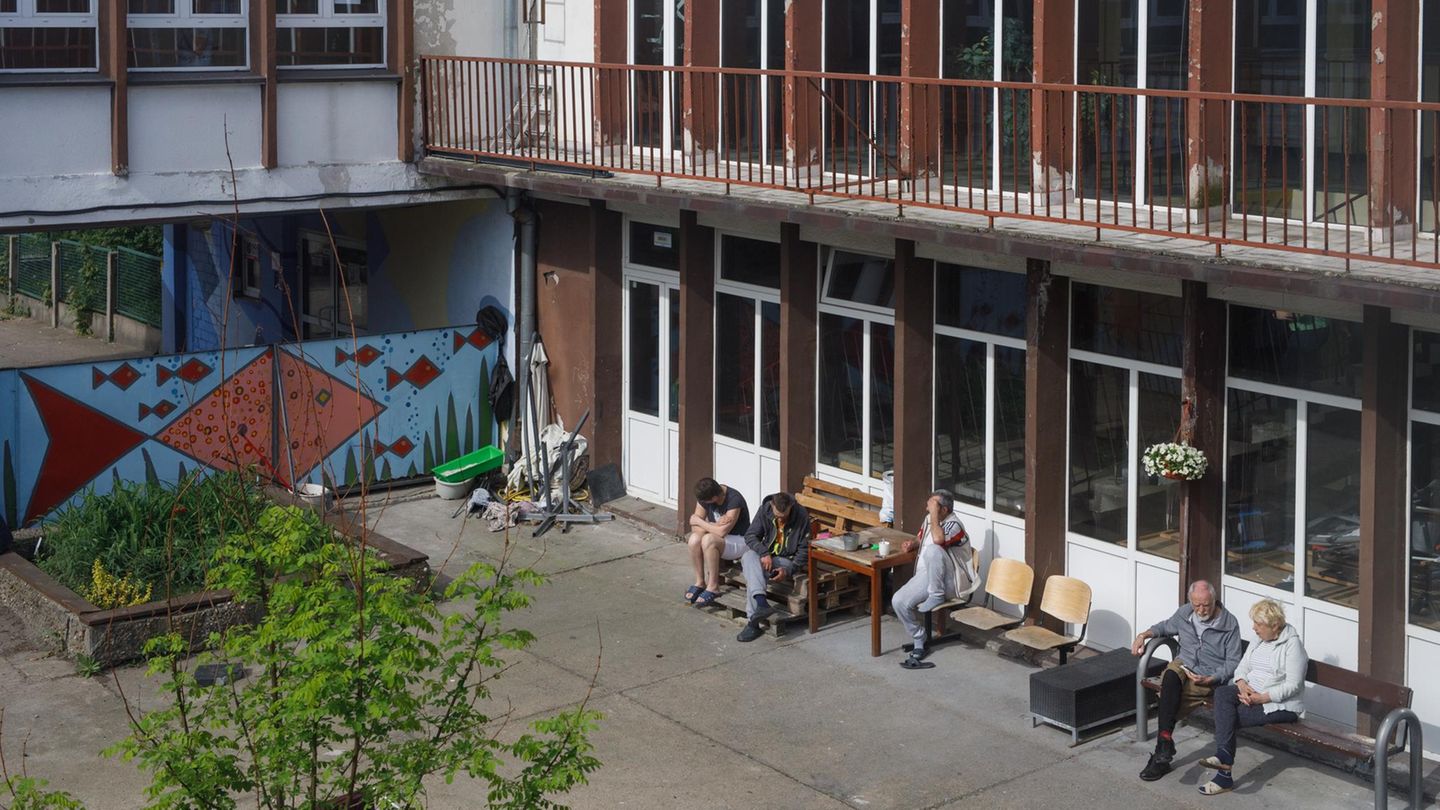 Im Innenhof der Schule sitzen fünf Menschen in der Sonne und rauchen Im Innenhof der Schule sitzen fünf Menschen in der Sonne und rauchen