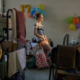 Olena lehnt an ihrem Bett, dahinter sind goldene Luftballons für den 17. Geburtstag ihrer Schwester