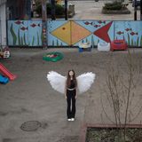 Ein Mädchen steht mit selbstgebastelten Engelsflügeln im Innenhof der Schule