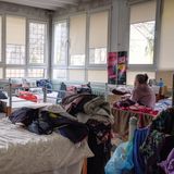 Eine alte Frau sitzt auf einem Bett in einem der Schlafzimmer und schaut aus dem Fenster