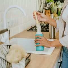 Eine Frau reinigt eine Flasche mit einer Bürste