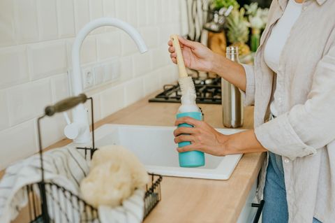 Eine Frau reinigt eine Flasche mit einer Bürste