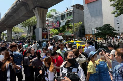In Bangkok stehen Menschen auf einer breiten Straße dicht an dicht – ins Freie getrieben durch ein Erdbeben