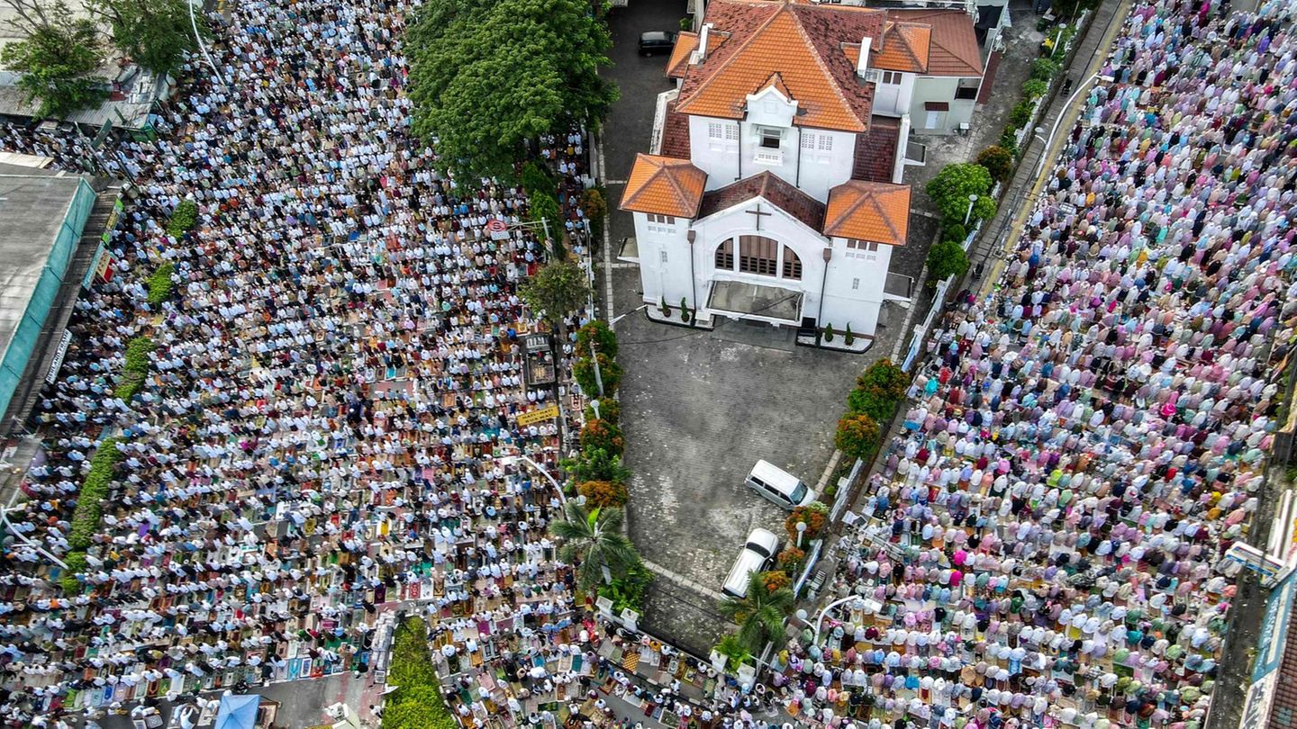 Jakarta, Indonesien. Muslime beten gemeinsam während des Zuckerfests zum Ende des Ramadans. Die Luftaufnahme zeigt mitten unter den Betenden eine Kirche. Etwa zehn Prozent der Menschen in Indonesien sind christlich, die Mehrheit protestantisch. Traditionell ist der Islam gegenüber Christen tolerant und friedlich, aber in den vergangenen Jahrzehnten hat ein erstarkender Islamismus häufig für Konflikte und Gewalt gegen Minderheiten gesorgt