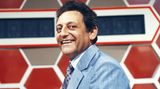 Quizmaster Hans Rosenthal lacht, gekleidet in ein blaues Jackett, in die Kamera