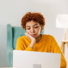 Vitamine gegen Müdigkeit: Junge Frau sitzt müde am Laptop