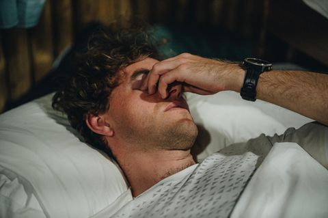 Bebilderunge "Schlaf": Ein junger Mann liegt im Bett und reibt sich die Augen