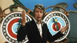 Rudi Carrell im schwarzen Sakko in der Show "Am laufenden Band", er gestikuliert mit den Händen