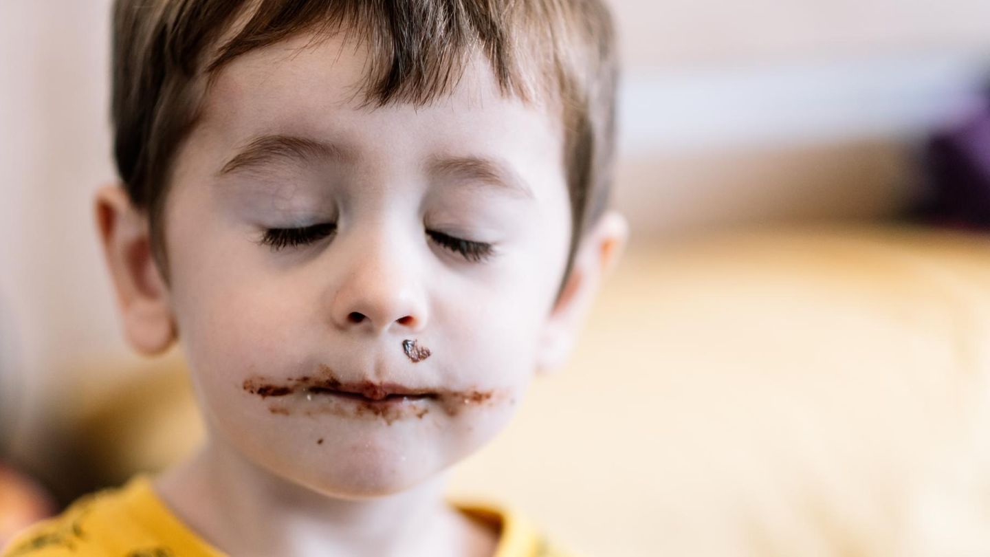 Kinder: Ein kleiner Junge mit schokoladenverschmiertem Mund und geschlossenen Augen