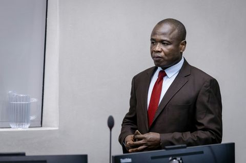 Dominic Ongwen trägt einen schwarzen Anzug und eine rote Krawatte