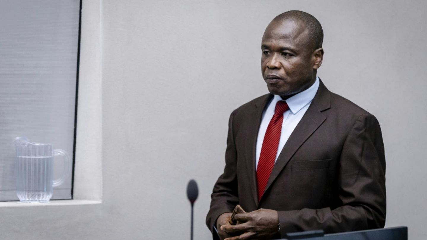 Dominic Ongwen trägt einen schwarzen Anzug und eine rote Krawatte