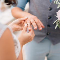 Braut steckt ihrem Bräutigam den Ehering an den Finger