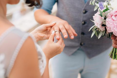 Braut steckt ihrem Bräutigam den Ehering an den Finger