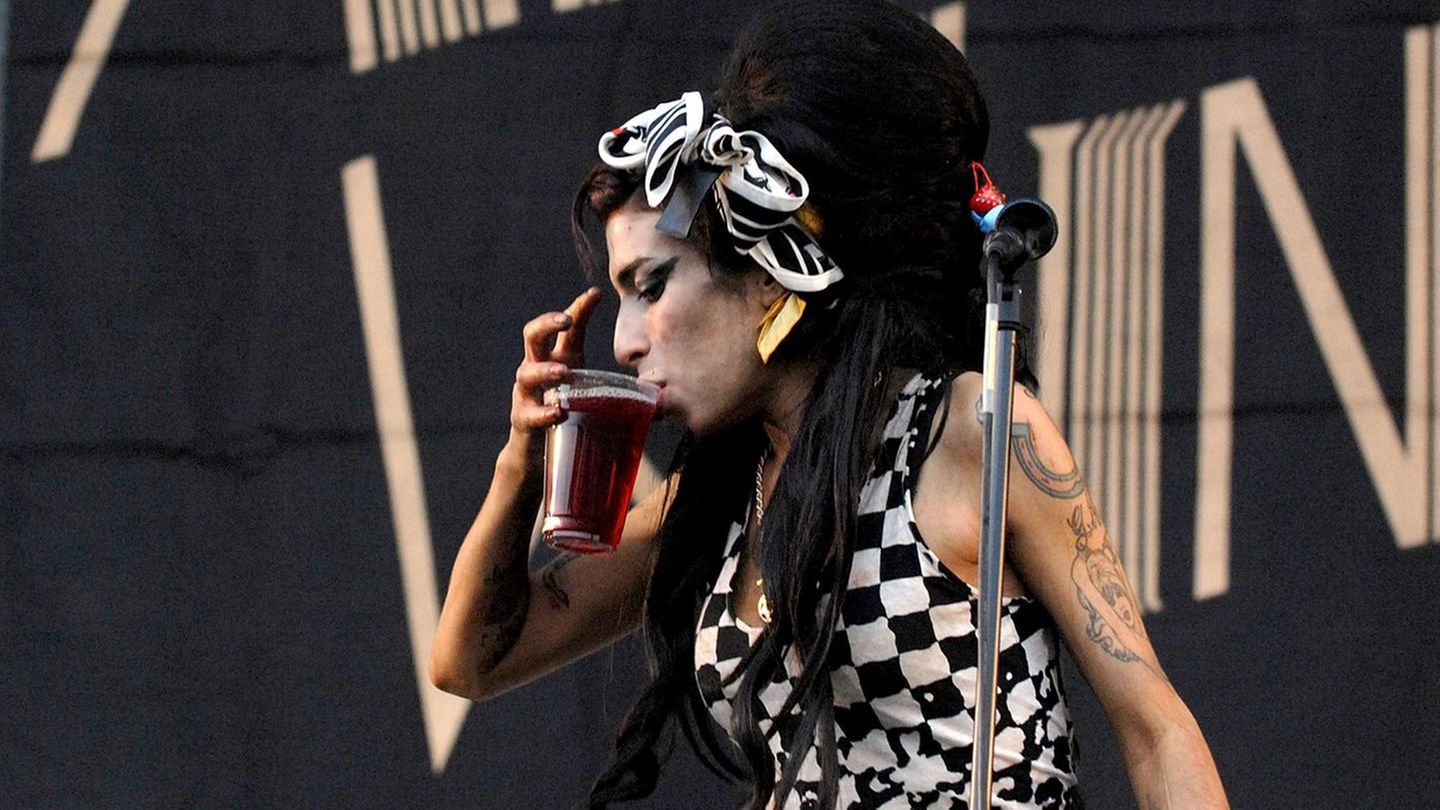 Amy Winehouse mit Drink in der Hand auf der Bühne
