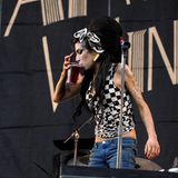 Amy Winehouse mit Drink in der Hand auf der Bühne