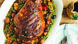 Gebratene Lammkeule mit Erbsen und Perlzwiebeln (Cosciotto d'agnello con piselli e cipolline)     Für 4 Personen  ½ Lammkeule (1,2 kg)  Salz und schwarzer Pfeffer aus der Mühle  etwas natives Olivenöl extra  150 ml trockener Weißwein  300 g Perlzwiebeln oder Schalotten  24 Taggiasca-Oliven (aus dem italienischen Feinkostladen), entsteint  2 Knoblauchzehen, leicht zerdrückt  4 Sardellenfilets, grob gehackt  150 g TK-Erbsen     Für einen besonderen Anlass oder als Sonntagsbraten ist dieses Gericht einfach perfekt. Die Kombination aus Perlzwiebeln, schwarzen Oliven, Sardellen, Knoblauch und Erbsen passt wunderbar zum saftigen Lammfleisch. Die Taggiasca-Oliven können Sie durch griechische Kalamata-Oliven ersetzen, die dem Gericht ein leicht säuerliches Aroma verleihen.  Den Backofen auf 200 °C vorheizen. Das Lammfleisch rundum mit Salz, Pfeffer und Olivenöl einreiben. In eine Bratreine legen und 20 Minuten im Ofen braten.  Die Hälfte des Weins zugießen und weitere 20 Minuten garen. Restlichen Wein, Perlzwiebeln, Oliven, Knoblauch und Sardellen zugeben, mit Alufolie abdecken und 70 Minuten schmoren.  Die Erbsen zufügen und 10 Minuten garen. Die Alufolie abnehmen und das Fleisch weitere 10 Minuten braten.  Aus dem Backofen nehmen und 5 Minuten ruhen lassen. Die Lammkeule auf einem Schneidebrett tranchieren und mit Gemüse und Bratensaft servieren