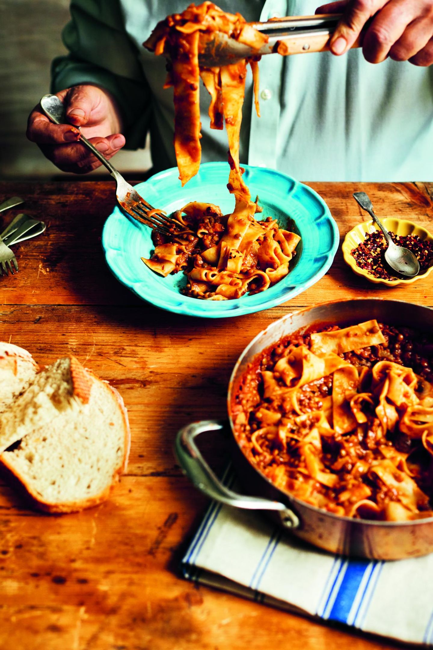 Vegane Linsen-"Bolognese" (Ragù vegano di lenticchie)     Für 6 Personen  280 g getrocknete braune oder grüne Linsen  5 EL natives Olivenöl extra, plus mehr zum Beträufeln  1 kleine Zwiebel, fein gehackt  1 Stange Staudensellerie, fein gehackt  1 kleine Karotte, fein gewürfelt  100 g Kürbis, fein gewürfelt  2 Knoblauchzehen, davon 1 zerdrückt  2 Lorbeerblätter  200 g braune Champignons, geputzt und in feine Scheiben geschnitten  400 ml Tomatenpassata  ca. 900 ml heiße Gemüsebrühe  Salz  500 g Pappardelle (ohne Ei)  getrocknete Chiliflocken zum Servieren (nach Belieben)     Linsen stellen die perfekte Alternative zum Fleisch der traditionellen Bolognesesauce dar. Das mit ein paar Grundzutaten leicht zuzubereitende Gericht ergibt eine herzhafte, nährstoffreiche Mahlzeit. Zum Ragù passen Pappardelle ganz hervorragend, aber Sie können auch Tagliatelle, Penne, Farfalle oder einfach Ihre Lieblingspasta nehmen. Damit es noch aromatischer wird, habe ich Kürbis und Pilze zugefügt. Oder Sie probieren stattdessen ein anderes Gemüse bzw. lassen beides einfach weg. Nur die Soffritto-Grundzutaten Zwiebel, Staudensellerie und Karotte dürfen nicht fehlen.  Die Linsen in einem Sieb unter fließendem kalten Wasser abspülen. Das Olivenöl in einem Topf erhitzen. Zwiebel, Staudensellerie, Karotte, Kürbis und Knoblauch bei mittlerer Hitze einige Minuten anschwitzen. Dann Linsen, Lorbeerblätter und Champignons unterrühren und einige Minuten garen.  Passata und Brühe zugießen und zum Kochen bringen. Die Temperatur reduzieren und 1 Stunde leise köcheln lassen, bis die Linsen gar sind. Je nach Linsensorte benötigt man mehr oder weniger Brühe. Deshalb die Brühe nach und nach zufügen.  Gegen Ende der Garzeit Wasser mit Salz in einem großen Topf zum Kochen bringen und die Pasta al dente garen. Die Pasta mit einer Küchenzange zur Linsen-"Bolognese" geben, gut vermengen und etwas heißes Pastakochwasser zugießen, um die Sauce dünnflüssiger zu machen.  Vom Herd nehmen, mit Olivenöl beträufeln, nach Belieben mit Chiliflocken bestreuen und servieren