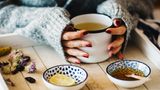 Ostern-Völlerei: Hände umfassen Teetasse
