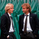 Jürgen Klinsmann und Rudi Völler treffen sich in Italien, beide tragen einen schwarzen Anzug.