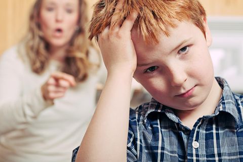 Eine Junge fasst sich an den Kopf, die Mutter hinter ihm schimpft