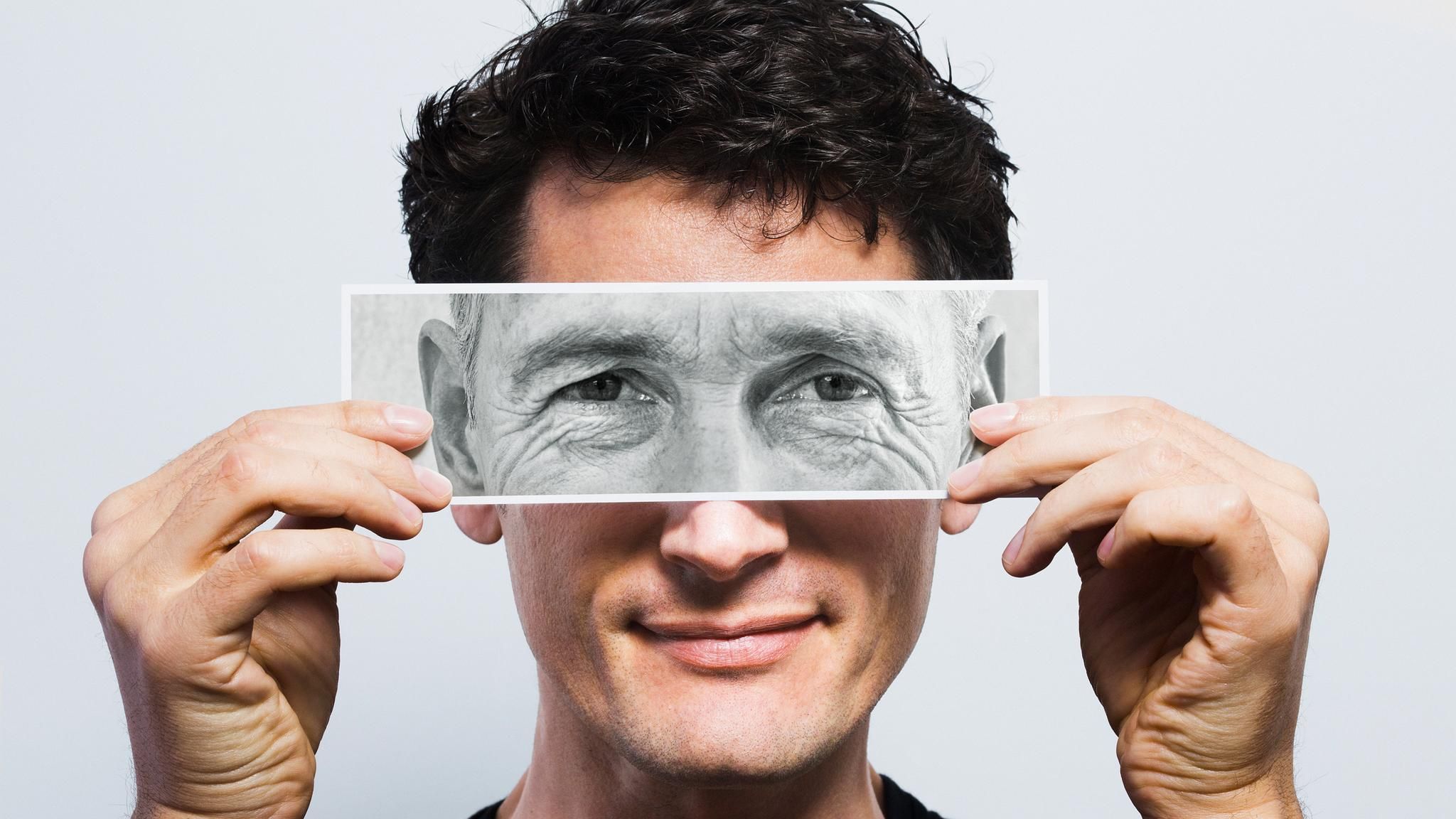 Zum Botox-Text einer Schönheitschirurgin: Ein Mann hält ein Schwarzweiß-Foto seiner Augen vor sein Gesicht