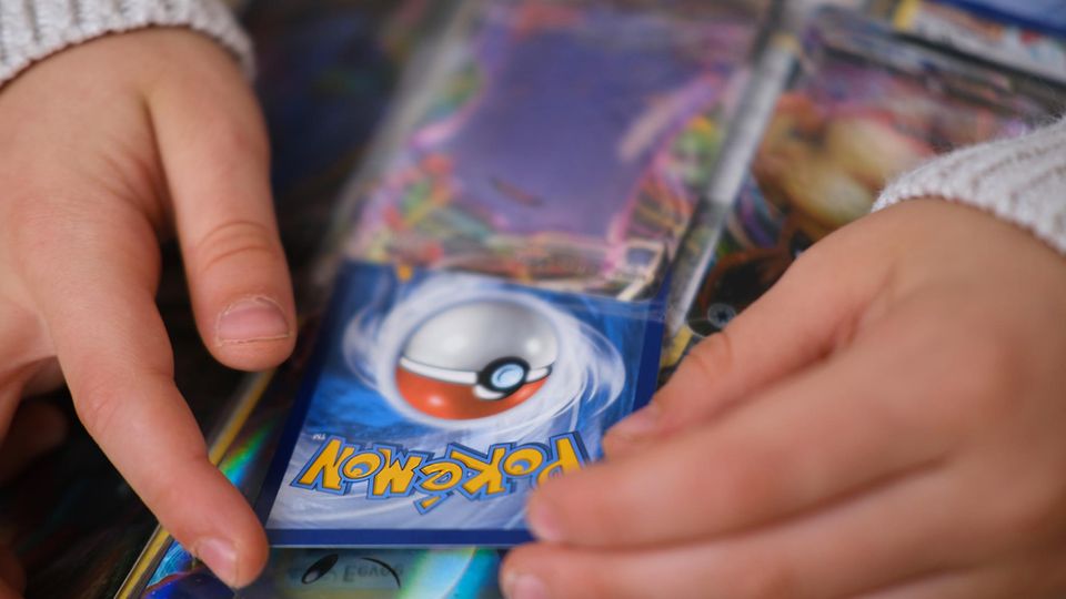 Jemand schiebt eine Pokémon-Karte in einen Sammelordner