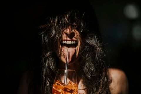 Rausch ohne Alkohol: Frau mit Aperolglas streckt die Zunge heraus