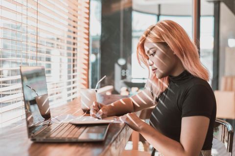 Generation Z Symbolbild: Junge Frau mit rosa Haaren arbeitet konzentriert am Laptop
