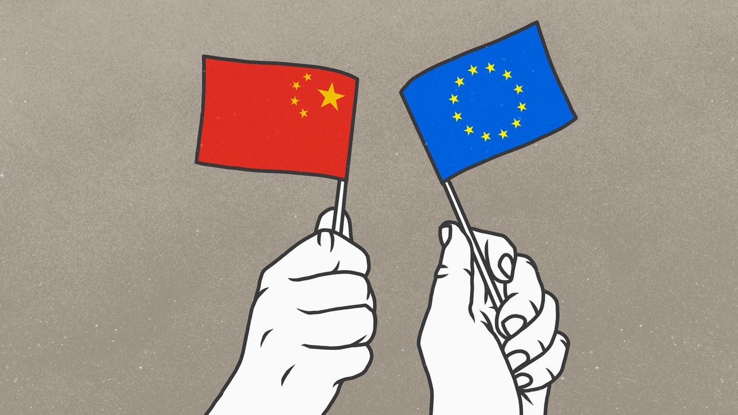 Zwei Hände halten Fahnen von China und der EU