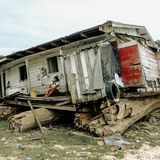 Eine Frau sitzt vor ihren zerstörten Haus