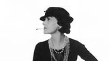 Coco Chanel 1935, sie trägt einen Hut, blickt zur Seite und hat eine Zigarette im Mund