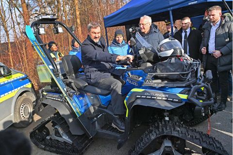 Markus Söder mit einem Polizeifahrzeug