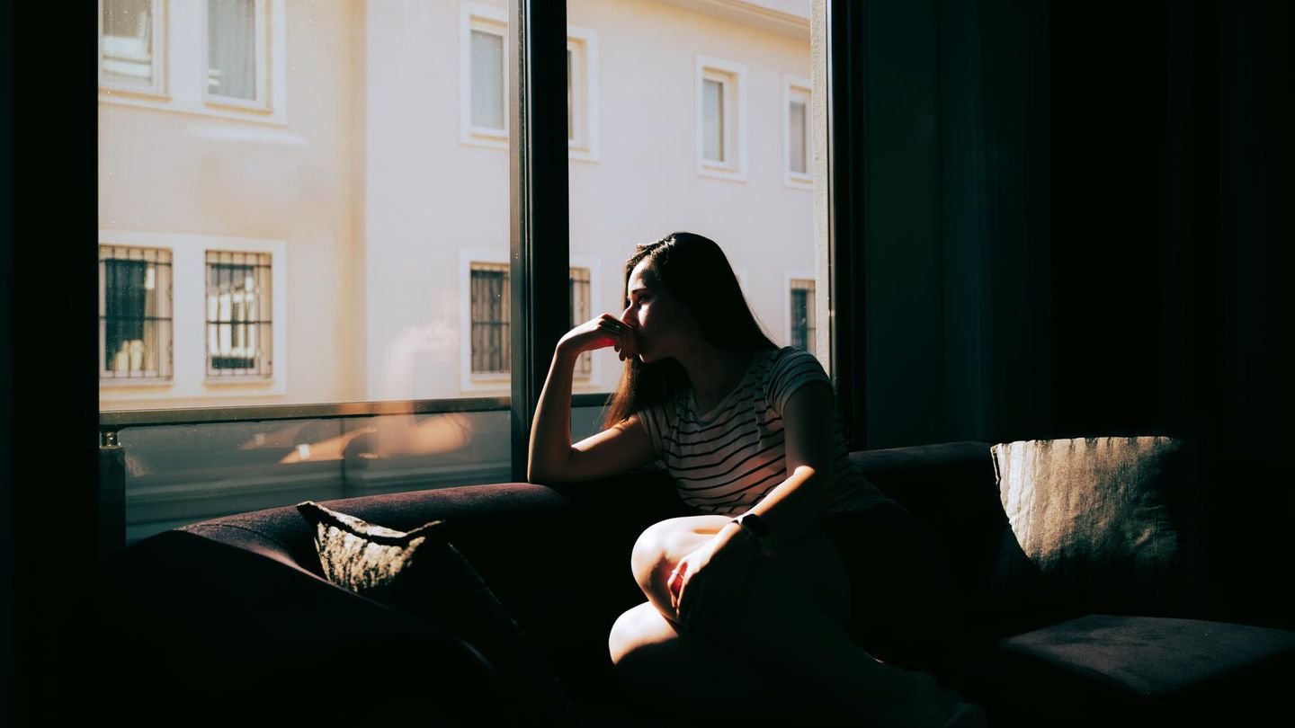 Eine Frau sitzt alleine am Fenster und denkt nach – über Beziehungen und Einsamkeit?