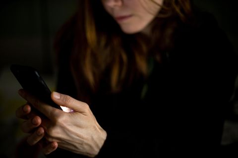 Frau hält ein Smartphone, nur ihr Kinn und Mund sind im Bild