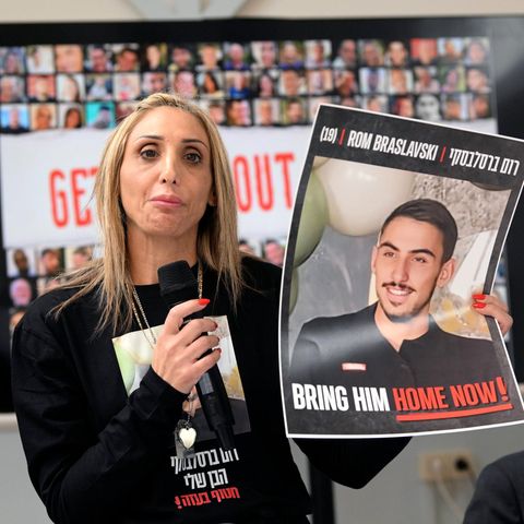 Eine Frau hält ein Plakat mit einem Foto der israelischen Geisel Rom Braslavski hoch