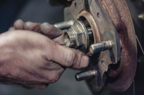 Eine Hand an einer verrosteten Schraube