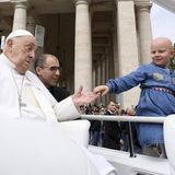Ein Kind ohne Haare wird zu Papst Franziskus ans "Papamobil" gereicht, damit er es segnen kann.