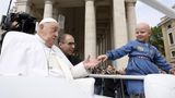 Ein Kind ohne Haare wird zu Papst Franziskus ans "Papamobil" gereicht, damit er es segnen kann.