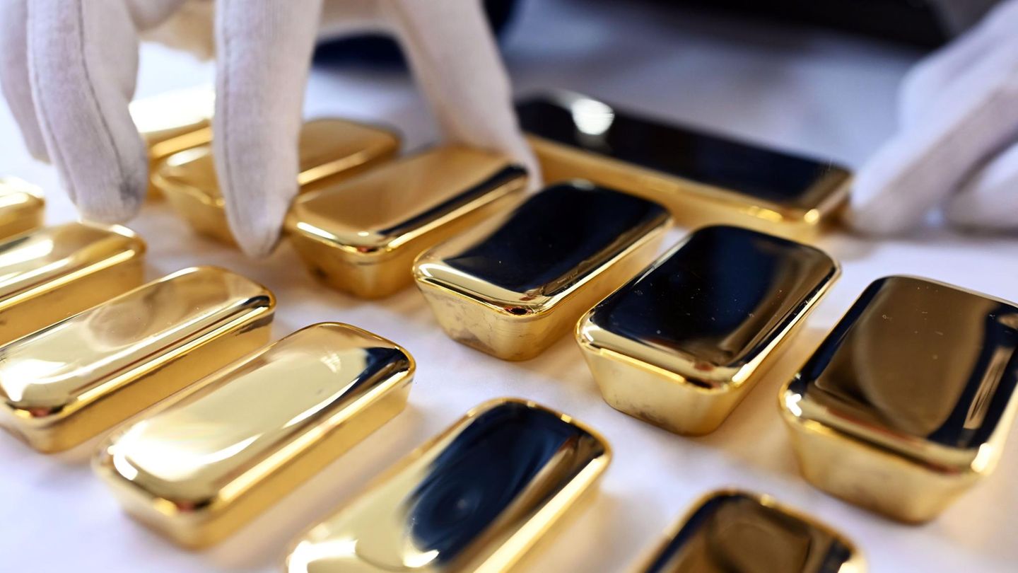 Goldpreis Symbolbild: Eine Hand in weißem Handschuh rückt einen Goldbarren zurecht