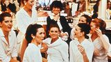 Coco Chanel in den 60er-Jahren im Kreise ihrer Mitarbeiterinnen. Im Hintergrund Regale mit Hüten