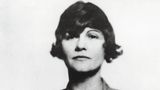 Ein Portrait von Coco Chanel, sie verschränkt die Arme vor dem Körper