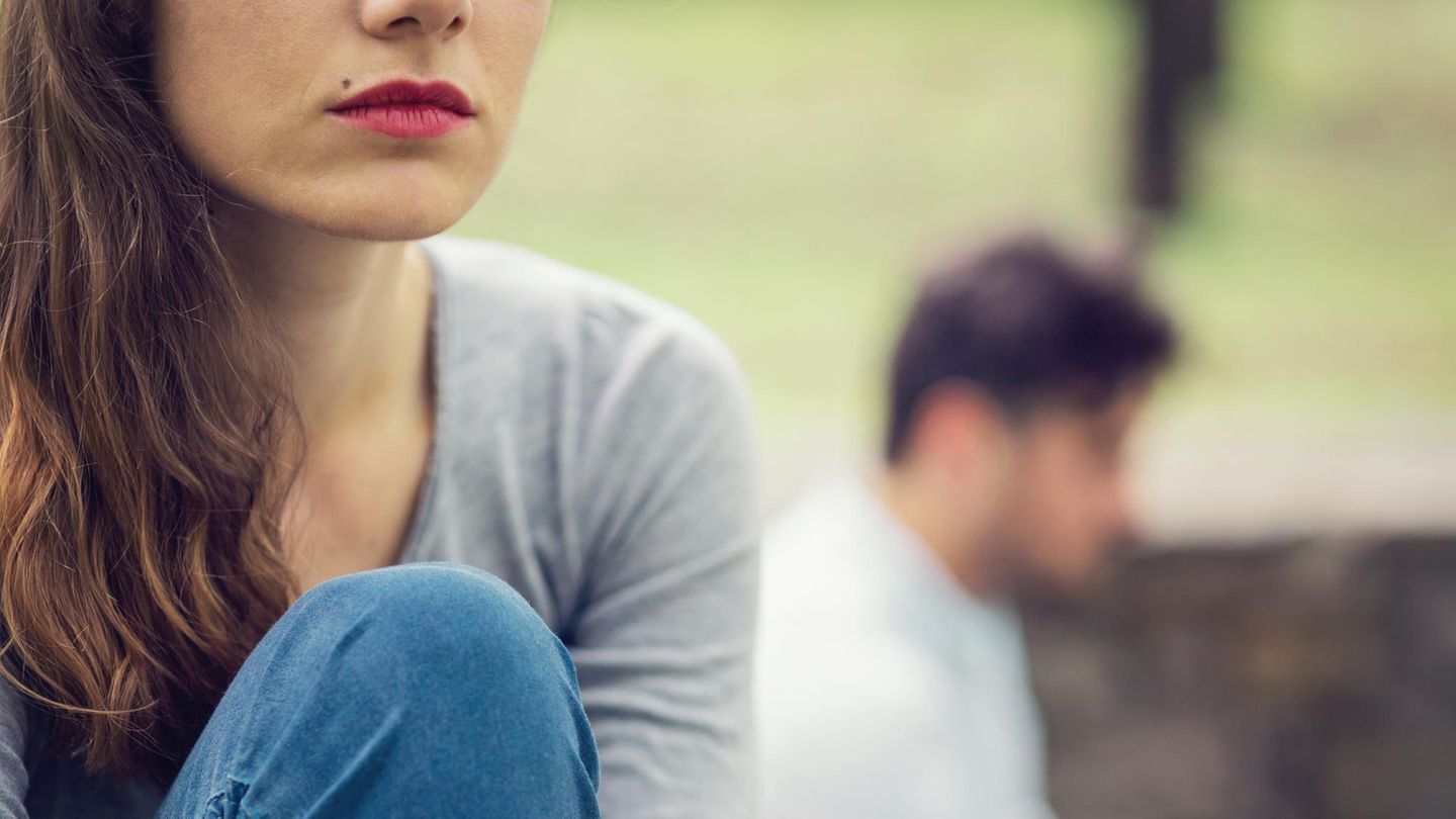 Ein Mann und eine Frau in einer Beziehung sitzen mit Abstand im Park