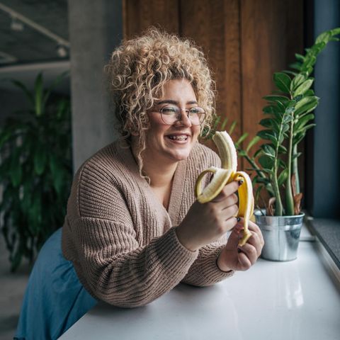 Blutzucker als Dickmacher: Frau isst eine Banane