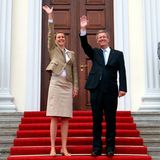 Bettina und Christian Wulff stehen auf einer Treppe und winken